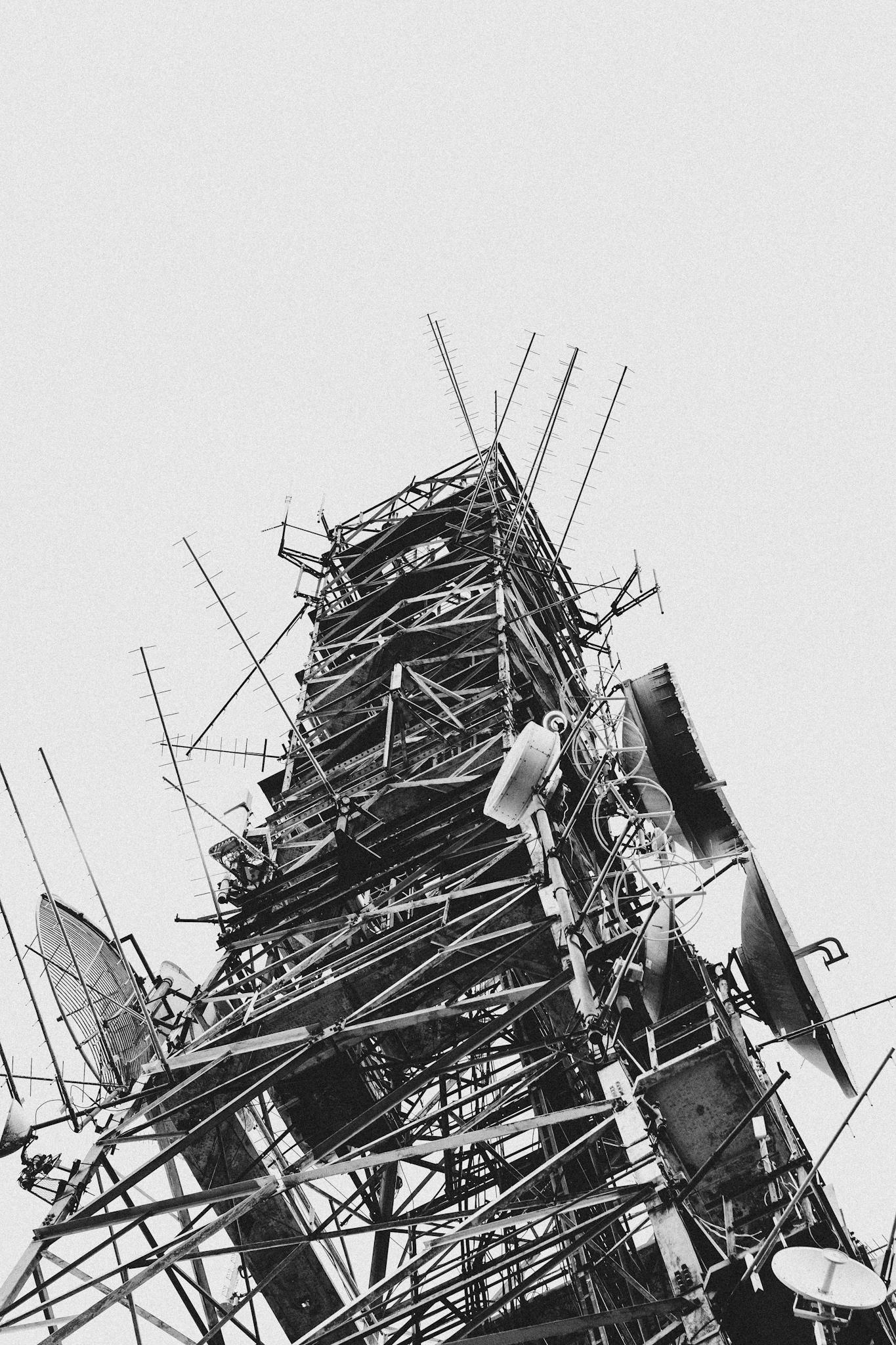 A monochromatic view of a towering radio communications structure capturing various antennas.